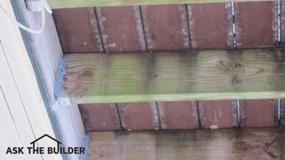 The floor joists under this deck are covered with unsightly mildew and algae. Photo Credit: Tim Carter