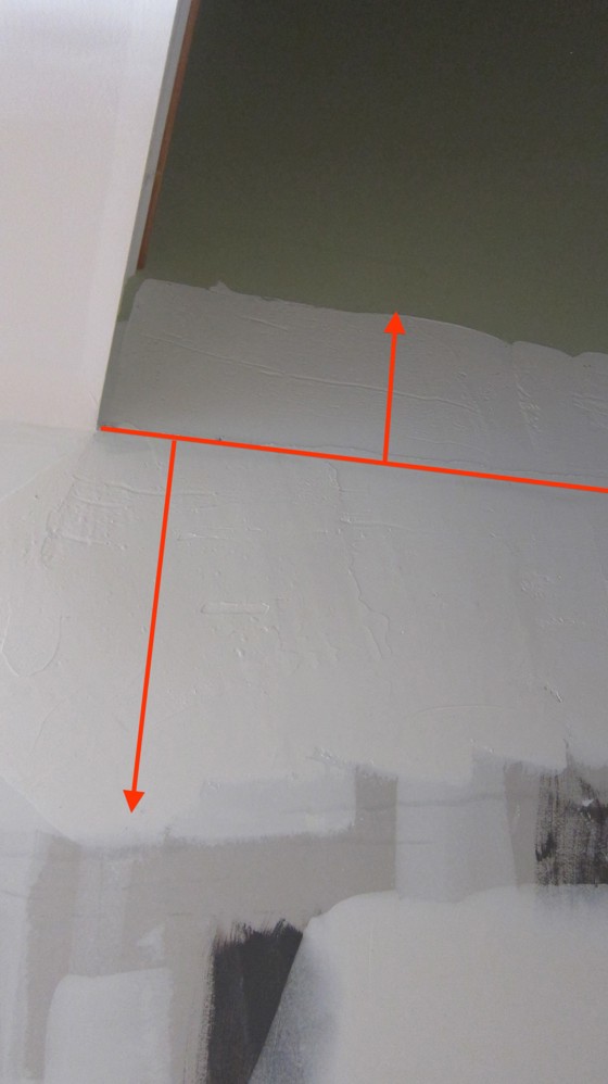 The slanted line runs along the high point of a hump in the wall. The shorter lines with arrow heads show the wide areas of joint compound added to hide the hump. Photo Credit: Tim Carter