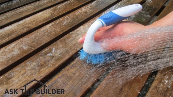 Use a scrub brush and clean water to rinse the cleaner from a fine teak table. Photo Credit: Tim Carter